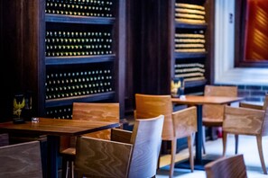 A restaurant interior with wooden tables and chairs, shelves with bottles, and a dark ambiance. - Palazzo Rosso (Poznań)