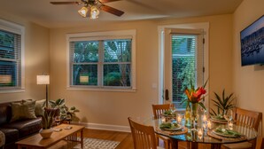 A dining area with a glass table, wooden chairs, and a vase with flowers. - Mesa Bliss - Tropical Oceanside Guest House on the Mesa (Santa Barbara)