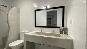 Un bany amb un vàter blanc, un mirall i una dutxa.