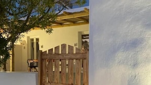 Una porta de fusta que dona a un edifici amb façana blanca i una escala.