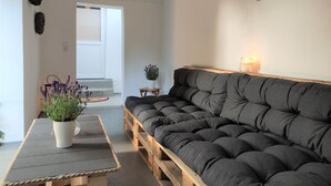 Un salon chaleureux avec un canapé gris foncé, une table basse en bois, un pot de lavande et une décoration en forme de cœur accrochée au mur.