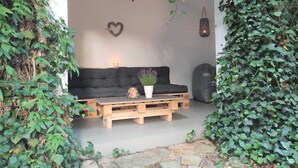 Un salon chaleureux avec un canapé noir, une table basse en bois, une plante en pot, une bougie et un cœur décoratif accroché au mur.