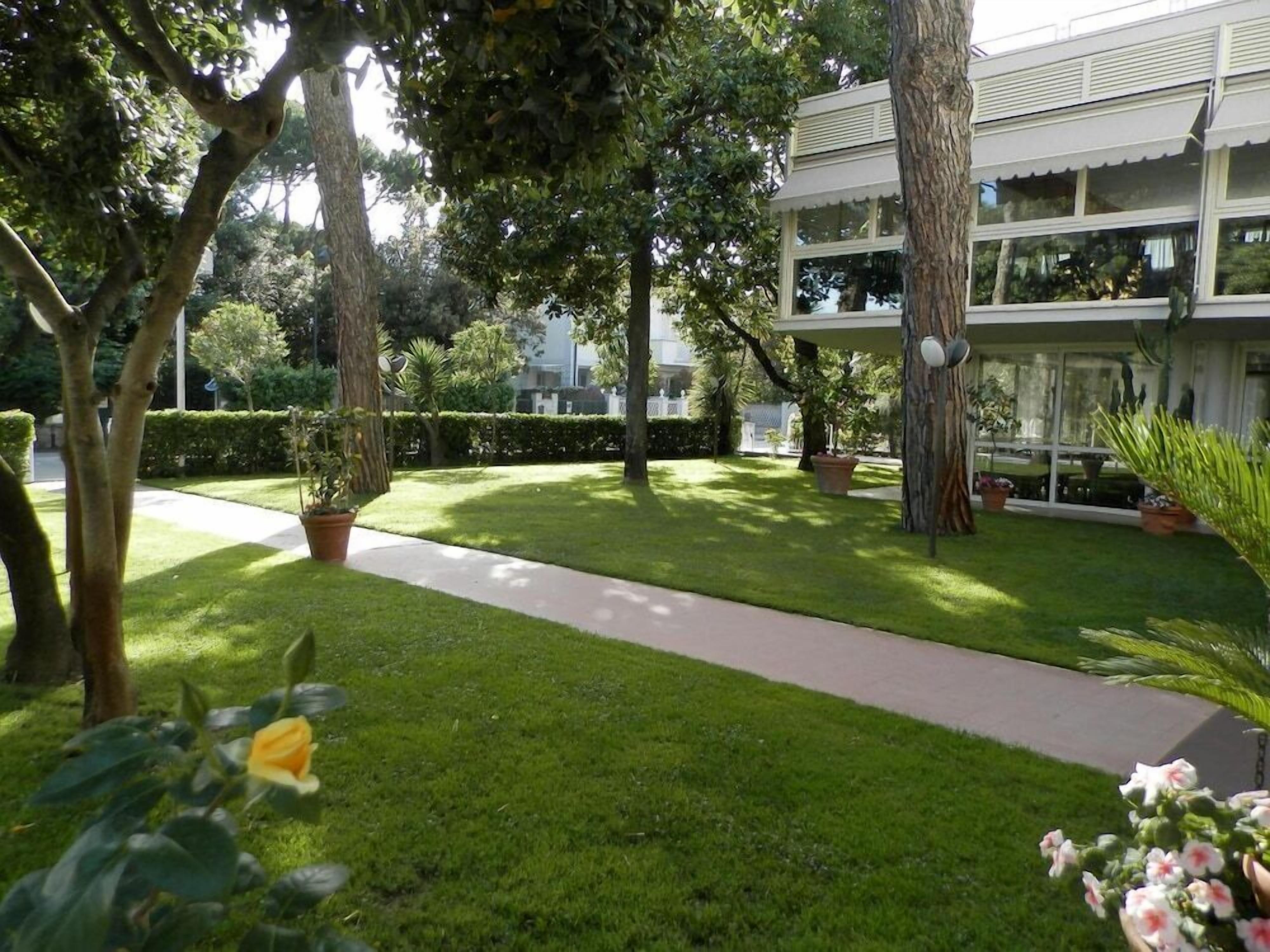 A well-maintained garden with a pathway leading to a building with large windows and a flat roof.