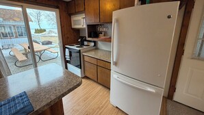Una cucina compatta con mobili in legno, un frigorifero bianco, un forno a microonde e un piano cottura.