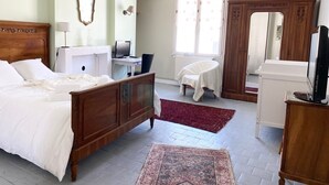 Una camera da letto con un letto di legno, una scrivania con un computer, una sedia, un armadio e una televisione.