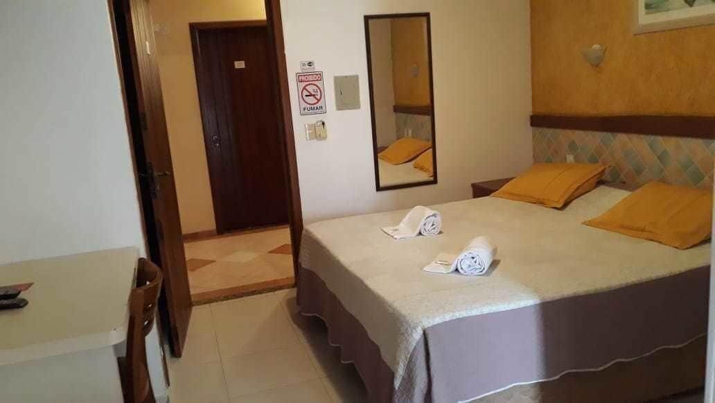 Une chambre d’hôtel avec un lit, deux oreillers, une serviette, un miroir et une porte.