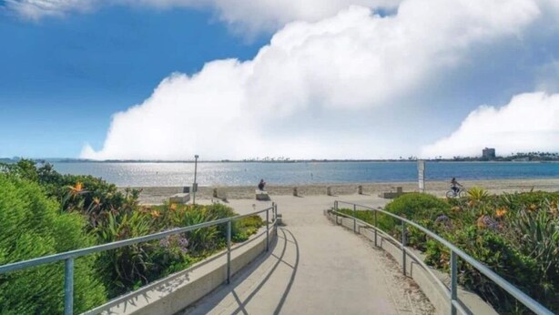 A coastal walkway with a clear view of the sea and a distant shoreline.