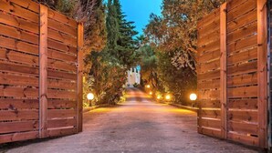 Un vialetto incorniciato da cancelli in legno che conduce a un edificio con ingresso illuminato.
