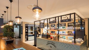 A food market counter with signs indicating service hours and a variety of food items. - The James Hotel Rotterdam (Rotterdam)