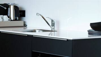 A modern kitchen with a stainless steel sink, a built-in oven, and a coffee machine.