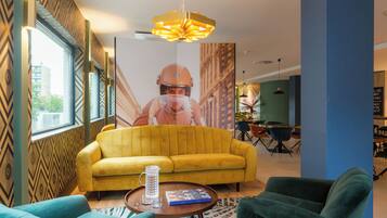 A modern interior with a yellow sofa, green armchairs, a coffee table, and a large poster on the wall.