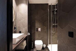 Un baño moderno con lavamanos, inodoro y ducha blancos.