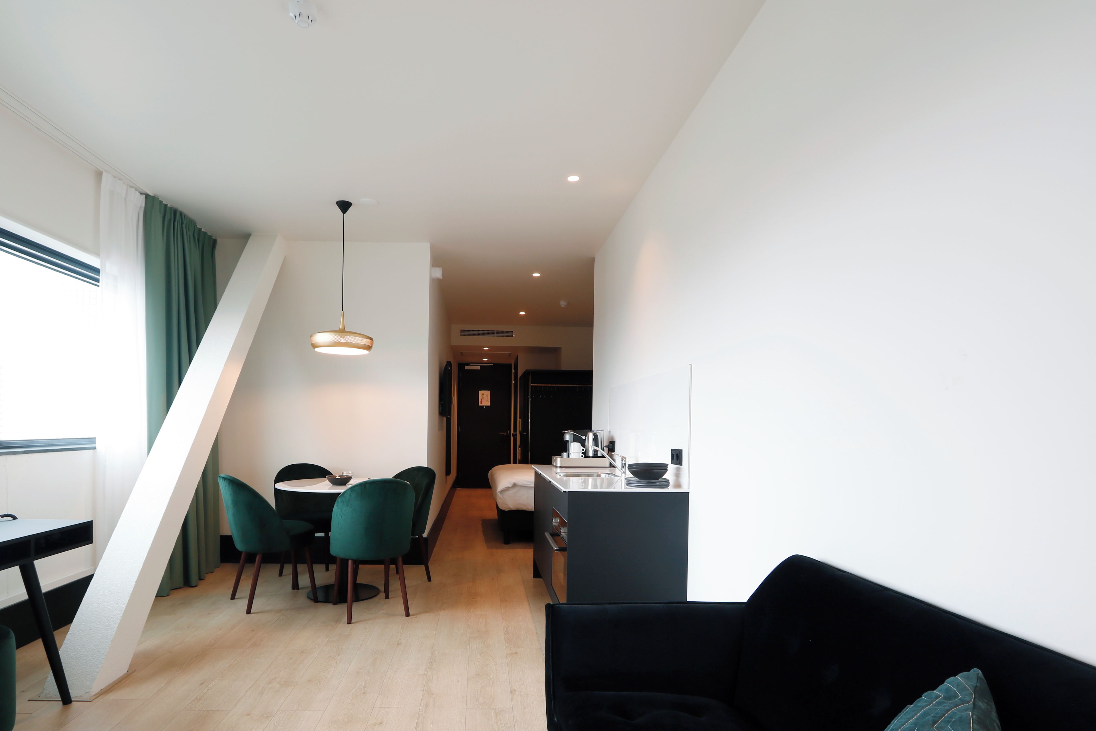 A modern interior with a dining area, a black sofa, and a kitchen.