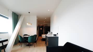 A modern interior with a dining area, a black sofa, and a kitchen.