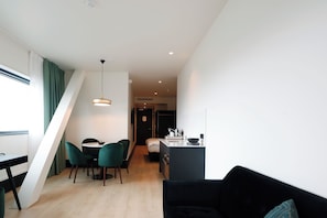 A modern interior with a dining area, a black sofa, and a kitchen. - The James Hotel Rotterdam (Rotterdam)