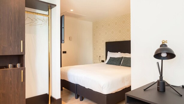 A modern hotel room with a bed, bedside table, lamp, and wardrobe. - The James Hotel Rotterdam (Rotterdam)