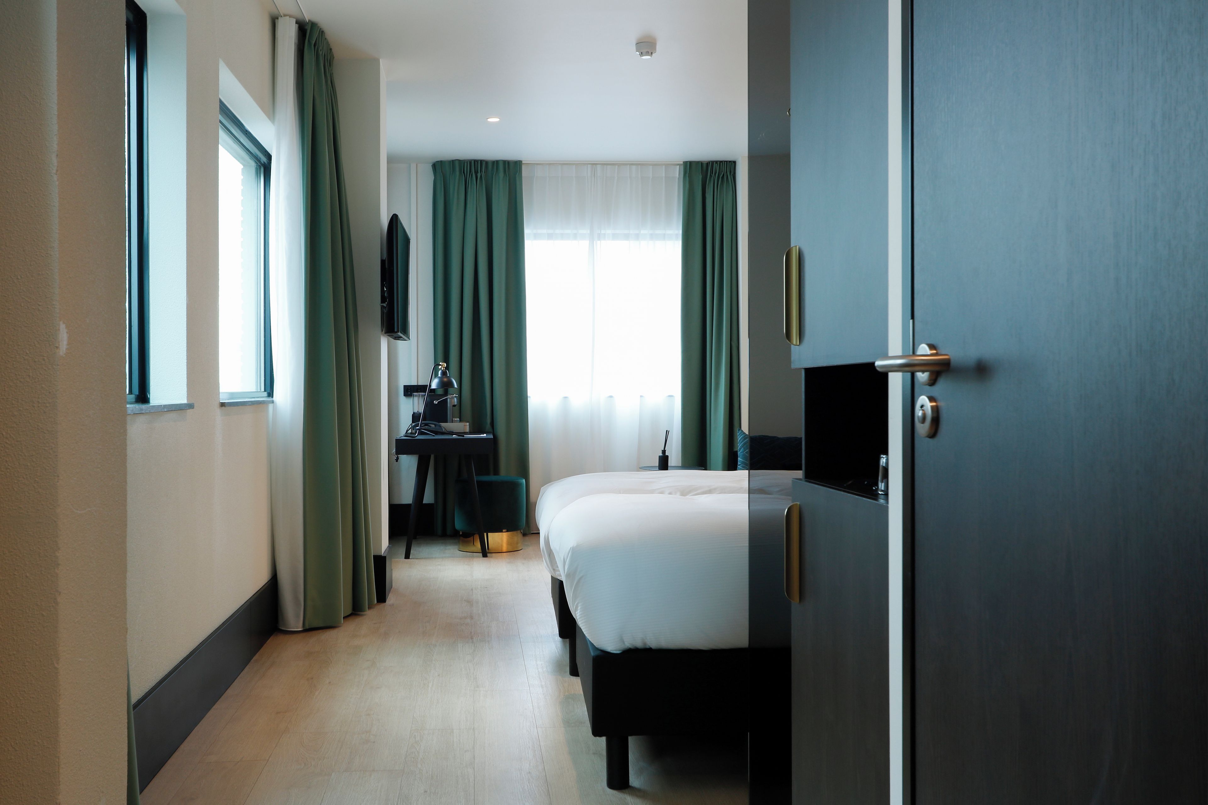 A hotel room with a bed, a desk, a chair, and a television.