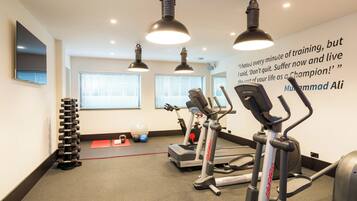 A gym with treadmills, elliptical machines, and a wall with motivational quote.