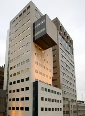 A modern high-rise building with a unique architectural design, featuring multiple floors and a prominent overhang. - The James Hotel Rotterdam (Rotterdam)