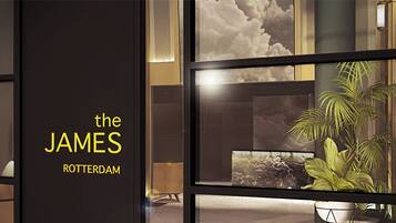A modern interior with a large window, a potted plant, and a wall with the text 'the JAMES ROTTERDAM'.