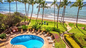 A pool area with lounge chairs, a small pool, and a view of the ocean and beach. - Kealia 402 Oceanfront Condo and Beautiful Secluded White-Sand Sugar Beach (Kihei)