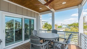 Une terrasse couverte avec un plafond en bois, une table ronde et quatre chaises.