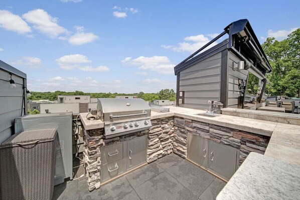 An outdoor patio with a built-in grill, stone accents, and a modern outdoor kitchen setup.