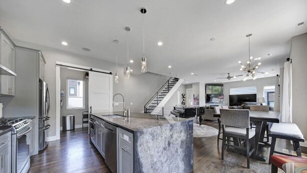 A modern kitchen with a marble island, stainless steel appliances, and a dining area with a piano.