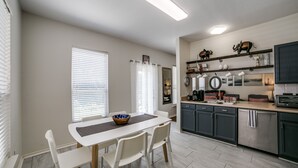 A modern kitchen with white cabinetry, a dining table with chairs, and a breakfast bar.