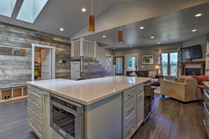 A modern kitchen with a central island, a dining area with a sofa, and a staircase leading to an upper level.