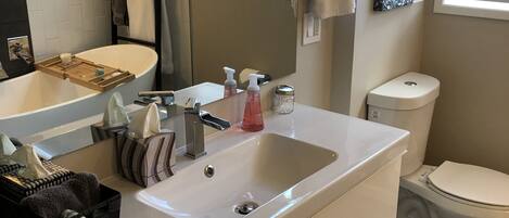 A modern bathroom with a white vanity, a sink, a mirror, and a toilet.