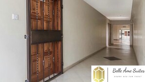 A hallway with a large wooden door, a light switch, and a logo for Belle Âme Suites.