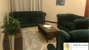 A living room with two dark green sofas, a coffee table, and a potted plant.