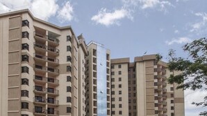 A multi-story residential building with balconies, a modern design, and a clear sky.