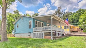 A two-story house with a porch, a visible American flag, and a well-maintained lawn. - Steps to Lake of the Ozarks: Family Home w/ Views! (Camdenton)
