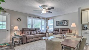 A spacious living room with a brown leather sofa, a dining table with four chairs, a ceiling fan, and a kitchen area with cabinets and a coffee maker. - Steps to Lake of the Ozarks: Family Home w/ Views! (Camdenton)