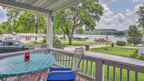 A covered outdoor area with a table and chairs, overlooking a lake with boats and a dock. - Steps to Lake of the Ozarks: Family Home w/ Views! (Camdenton)