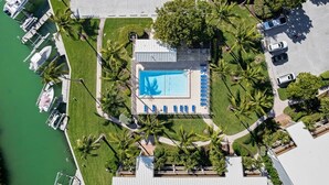Vista aérea de un resort con piscina, barcos y palmeras.