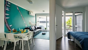 Une chambre moderne comprenant un coin repas, un canapé et un lit. Elle est dotée d’une grande fenêtre et d’une porte donnant sur un espace extérieur.