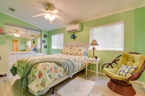 A bedroom with a bed, a chair, a nightstand, a lamp, and a ceiling fan.