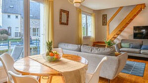Ein gemütliches Wohnzimmer mit einem Holzesstisch, einem grauen Sofa und einer Treppe.