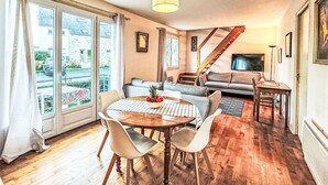 Ein gemütliches Wohnzimmer mit Essbereich, einer Treppe und großen Fenstern.
