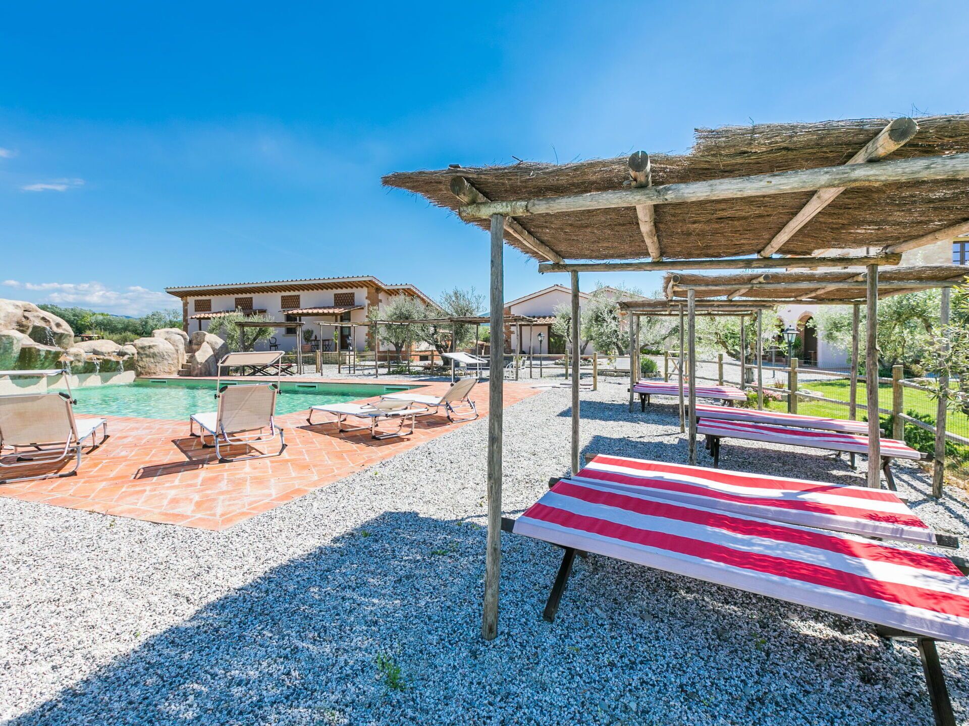 Zona de piscina amb gandules i una estructura de pergola.
