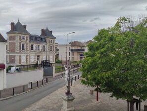 Eine Straße mit einer Statue, einem Baum und Gebäuden im Hintergrund.