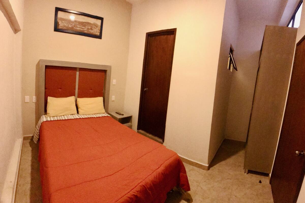 A bedroom with a bed, nightstand, and a wardrobe.