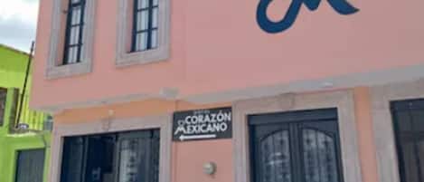 A pink building with a sign reading "CORAZON MEXICANO" and a logo with a blue 'C' and 'M'.
