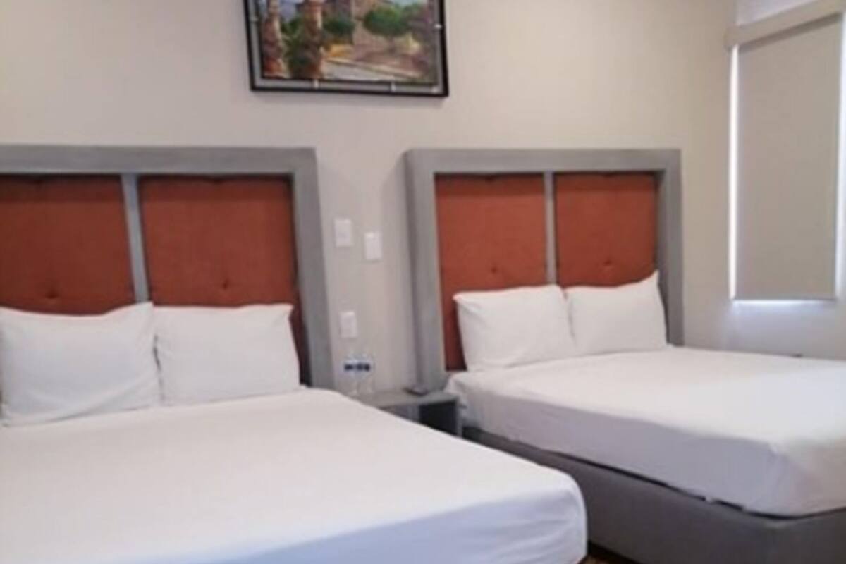A hotel room with two beds, a patterned floor, and a painting on the wall.