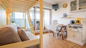 Ein kleines Zimmer mit Bett, Schreibtisch und einer Küchenzeile.
