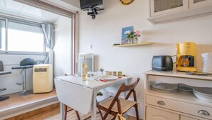 Eine kompakte Küche mit Essbereich, einem an der Wand montierten Fernseher und einem Fenster mit Vorhängen.