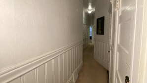 Un couloir aux murs blancs et au tapis beige.